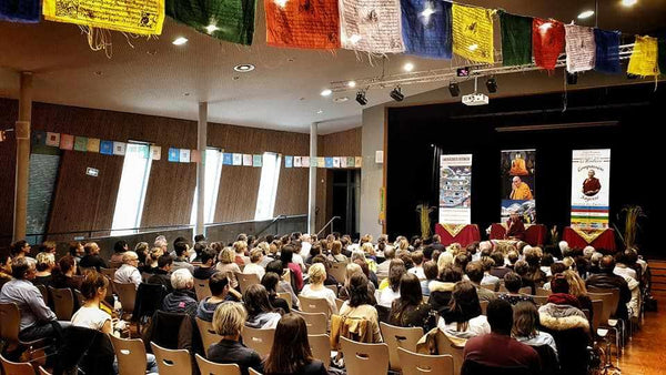 Conférence sur la méditation bouddhiste avec drapeaux tibétains et public attentif
