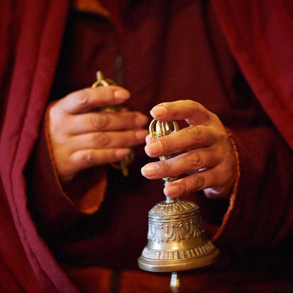 Mains tenant une cloche et un vajra bouddhistes, symboles de la philosophie tibétaine