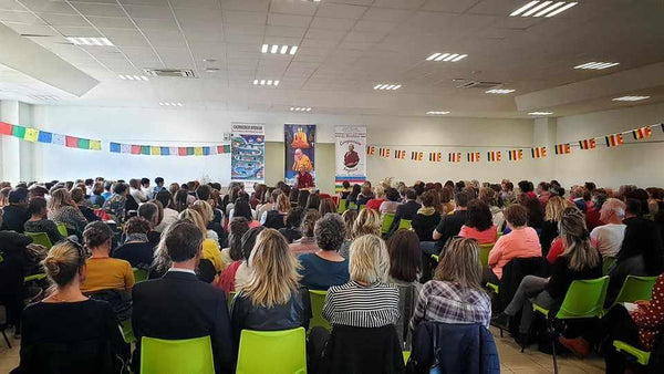 Conférence sur la méditation bouddhiste avec public assis, drapeaux tibétains et affiches de Lama Samten