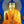Statue de Bouddha dorée avec robe orange, cheveux bleus et halo scintillant, symbole de la philosophie bouddhiste tibétaine