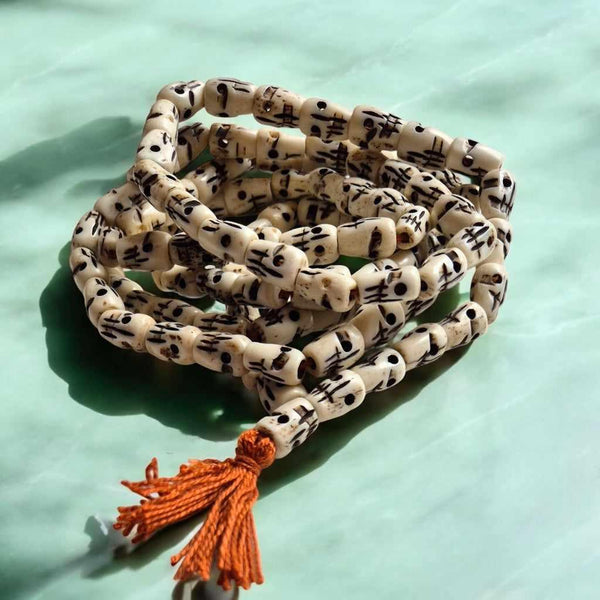 Mala bouddhiste tibétain en perles gravées avec pompon orange, objet de méditation et spiritualité