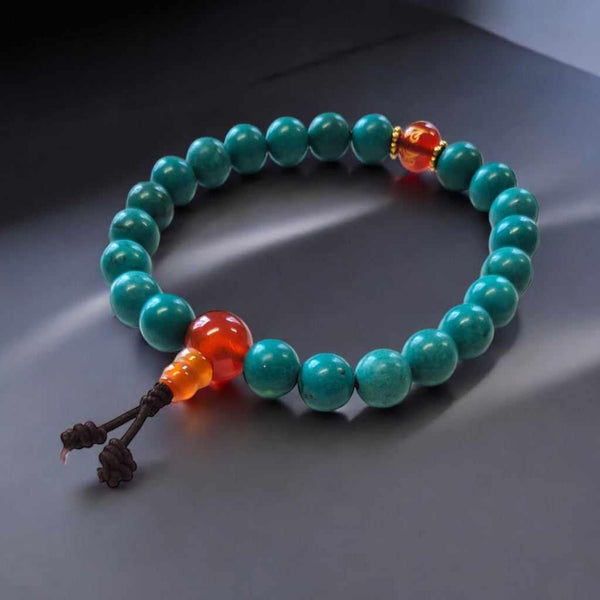 Bracelet bouddhiste en turquoise avec perles rouges et nœud tibétain, symbole de méditation et sagesse