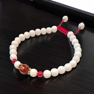 Bracelet bouddhiste blanc avec perle rouge gravée, symbole de méditation et philosophie tibétaine