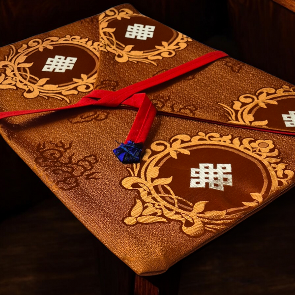 Coussin de méditation bouddhiste tibétain orné de symboles sacrés et ruban rouge