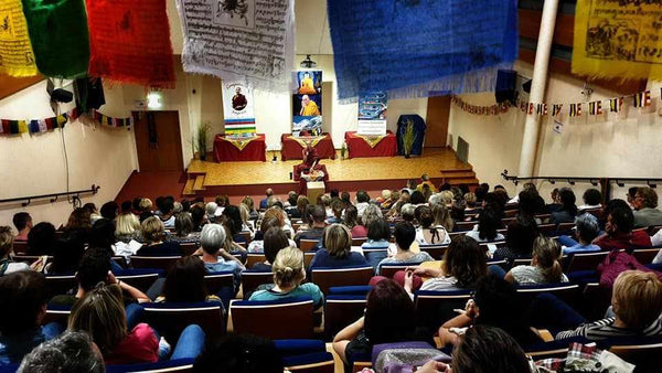 Conférence sur la méditation bouddhiste avec drapeaux tibétains et public attentif