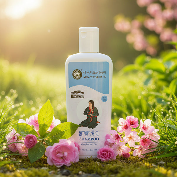 Shampoing tibétain Men-Tsee-Khang pour soins capillaires complets, entouré de fleurs roses en nature