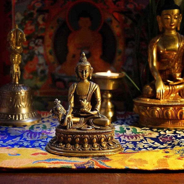 Statue bouddhiste en bronze sur tapis tibétain, bougie allumée, objets de méditation et culture himalayenne