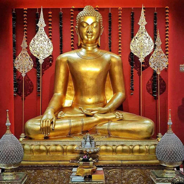 Statue dorée de Bouddha en méditation, décor tibétain et objets sacrés sur fond rouge