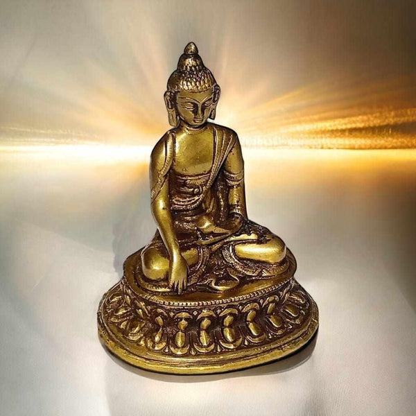 Statue dorée de Bouddha en méditation, style tibétain, sur socle orné, lumière douce