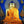 Statue de Bouddha dorée en robe orange, halo scintillant, décor tibétain traditionnel