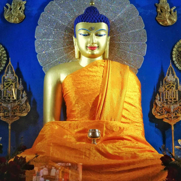 Statue de Bouddha dorée en robe orange, halo scintillant, décor tibétain traditionnel