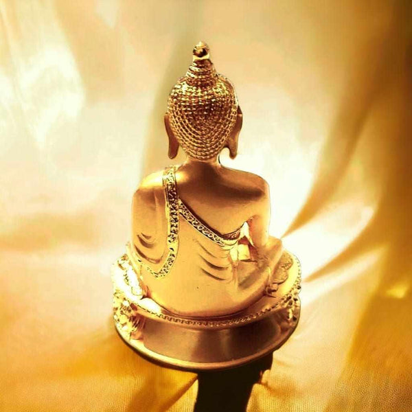 Statue dorée de Bouddha en méditation, dos tourné, sur fond soyeux doré, objet de philosophie bouddhiste