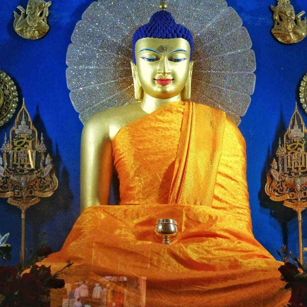 Statue de Bouddha dorée en robe orange, halo scintillant, symbole de méditation et philosophie bouddhiste tibétaine