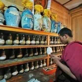 Moine bouddhiste tibétain sélectionnant des remèdes naturels de médecine tibétaine dans un échoppe traditionnelle