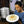 Femme souriante tenant un plat de momos tibétains frais, accompagnés d'une sauce orange, dans une cuisine traditionnelle.
