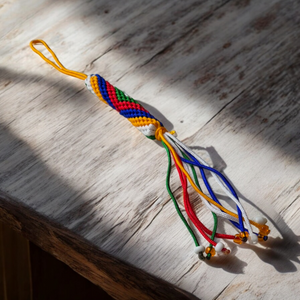Talisman tibétain tressé aux cinq couleurs, symbole de la philosophie bouddhiste, posé sur bois