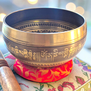 Bol chantant tibétain en métal gravé de mantras, posé sur coussin brodé, objet de méditation bouddhiste