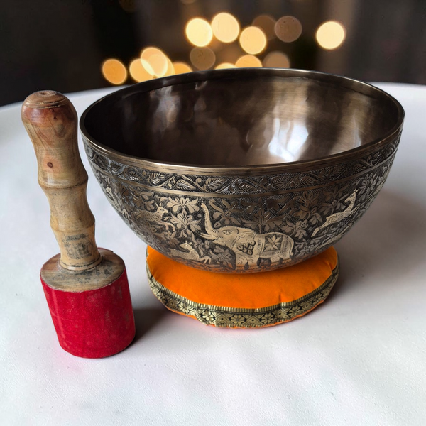 Bol tibétain gravé avec éléphant, maillet en bois et coussin orange, objet de méditation bouddhiste