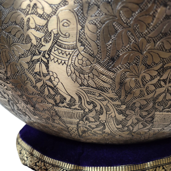 Bol tibétain gravé à motif d'éléphant et fleurs, posé sur coussin velours violet, art bouddhiste
