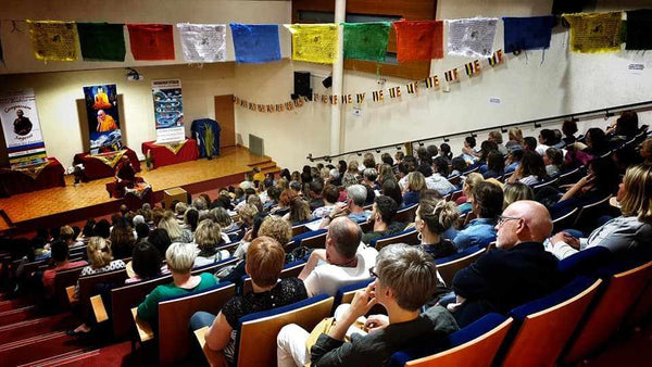 Conférence sur la méditation bouddhiste avec drapeaux tibétains et public attentif