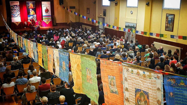 Conférence sur la méditation bouddhiste avec drapeaux tibétains et public attentif